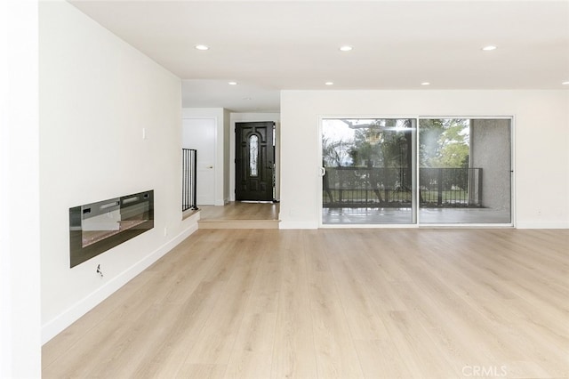 unfurnished living room featuring recessed lighting, light wood-type flooring, and baseboards