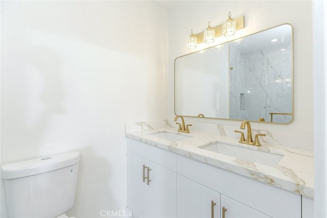 bathroom with a marble finish shower, double vanity, toilet, and a sink