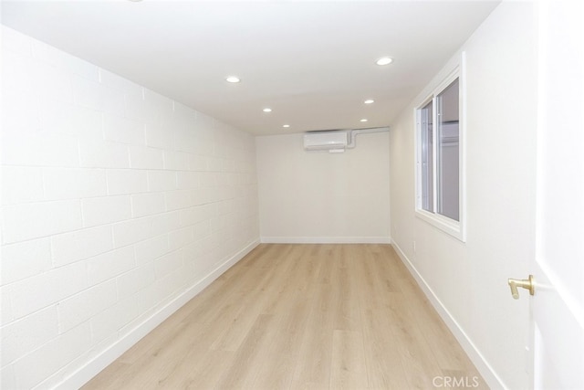 unfurnished room with recessed lighting, light wood-style flooring, a wall mounted air conditioner, and baseboards