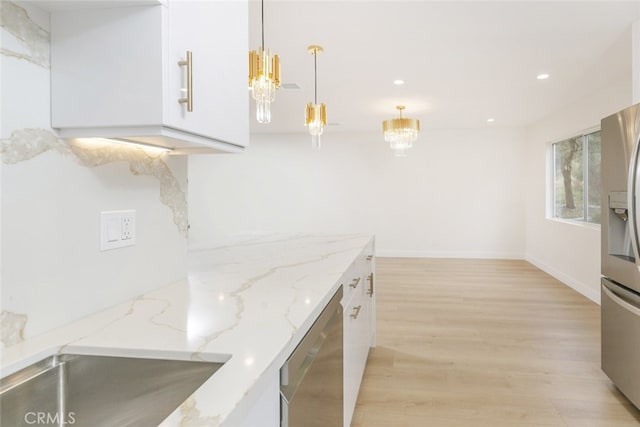 kitchen featuring a chandelier, light wood-style flooring, appliances with stainless steel finishes, and white cabinetry