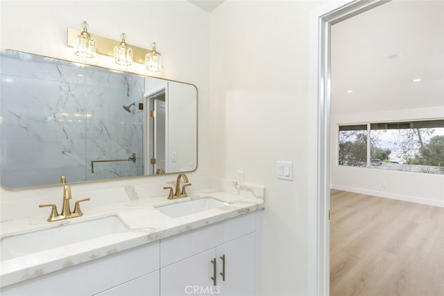 full bath featuring a marble finish shower, double vanity, wood finished floors, and a sink