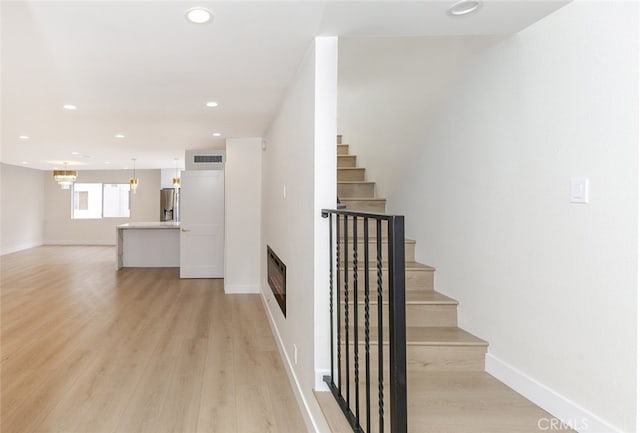 staircase featuring recessed lighting, visible vents, heating unit, and wood finished floors