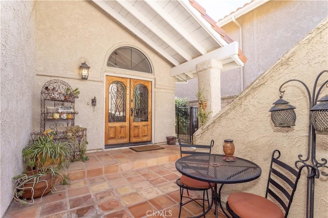 entrance to property featuring french doors and stucco siding