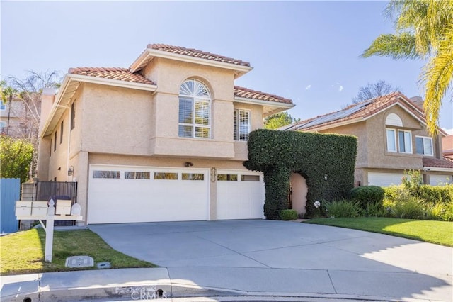 mediterranean / spanish house featuring a tiled roof, a garage, driveway, and stucco siding