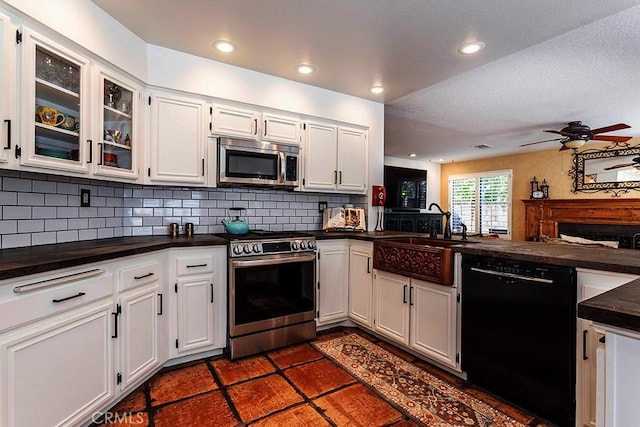 23461 Darcy Ln, Newhall, CA 91321 - kitchen with stainless steel appliances, dark countertops, a sink, a ceiling fan, and tasteful backsplash
