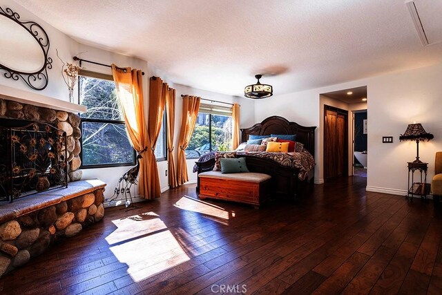 23461 Darcy Ln, Newhall, CA 91321 - bedroom with wood-type flooring, multiple windows, a stone fireplace, a textured ceiling, and baseboards