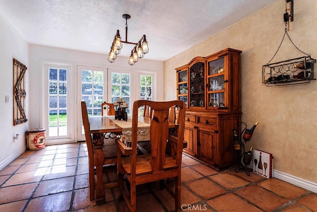 23461 Darcy Ln, Newhall, CA 91321 - dining room featuring a chandelier, baseboards, a textured ceiling, and stone tile floors