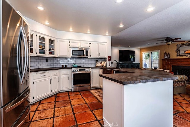23461 Darcy Ln, Newhall, CA 91321 - kitchen featuring stainless steel appliances, dark countertops, a peninsula, backsplash, and recessed lighting