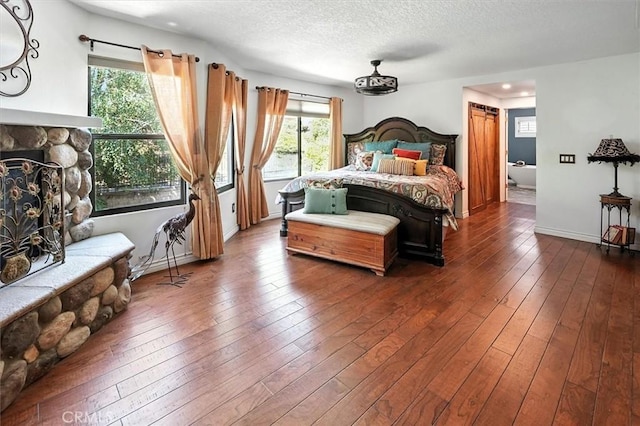 23461 Darcy Ln, Newhall, CA 91321 - bedroom with a stone fireplace, multiple windows, hardwood / wood-style floors, and a textured ceiling