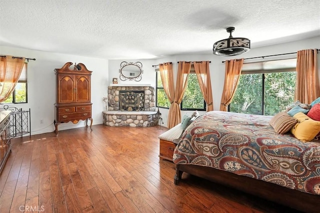23461 Darcy Ln, Newhall, CA 91321 - bedroom featuring a textured ceiling, wood-type flooring, multiple windows, and a stone fireplace