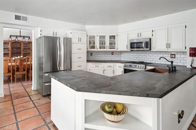23461 Darcy Ln, Newhall, CA 91321 - kitchen featuring appliances with stainless steel finishes, dark countertops, open shelves, decorative backsplash, and a peninsula