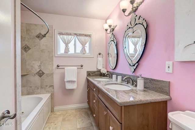 full bathroom featuring double vanity, toilet, baseboards, and a sink