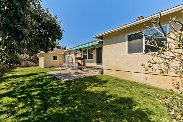 back of house with a yard, stucco siding, a patio, and fence