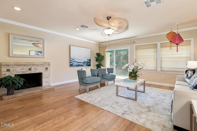 living room with visible vents, a ceiling fan, light wood-style flooring, and crown molding