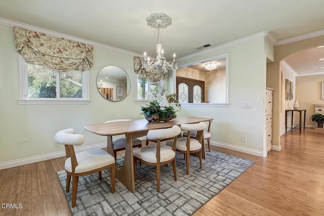 dining area featuring ornamental molding, visible vents, arched walkways, and light wood-type flooring