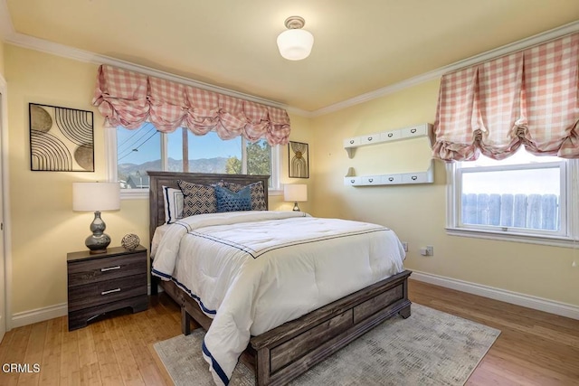 bedroom with wood finished floors, baseboards, and ornamental molding