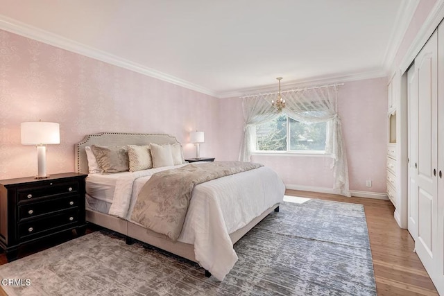 bedroom with a closet, baseboards, wood finished floors, and crown molding