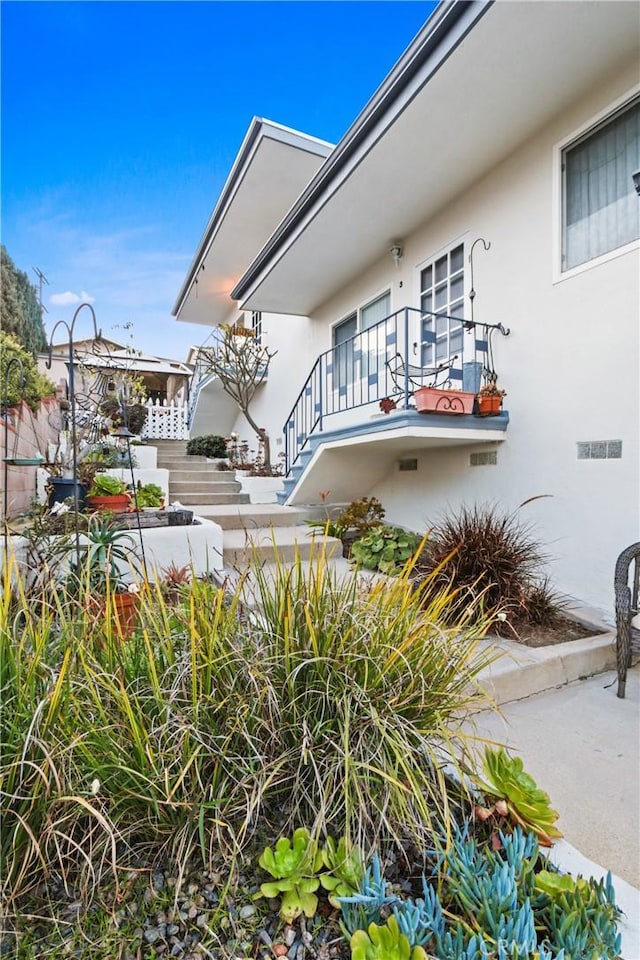 view of side of home featuring stucco siding and a balcony