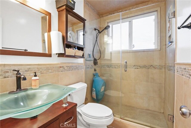 full bath featuring a shower stall, tile walls, and toilet