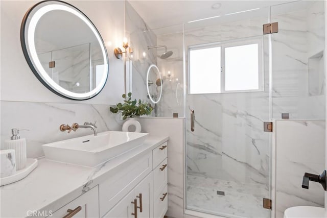 full bath with a marble finish shower, vanity, and tasteful backsplash