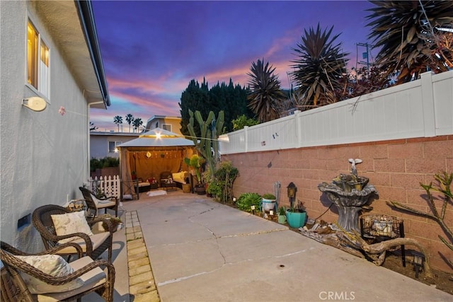 patio terrace at dusk with a gazebo and a fenced backyard