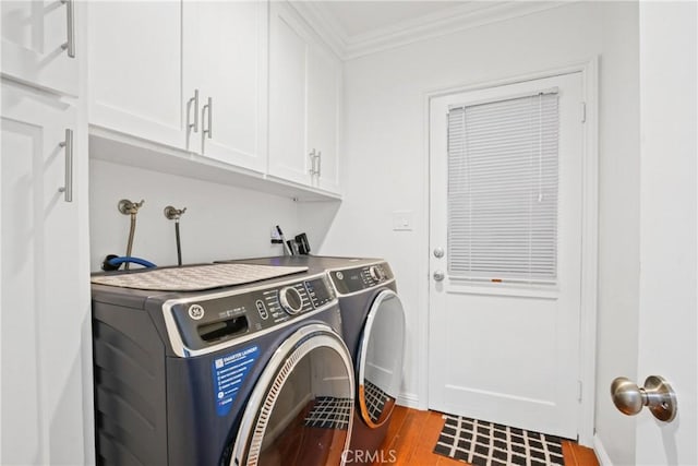 laundry area with washing machine and clothes dryer, baseboards, ornamental molding, wood finished floors, and cabinet space