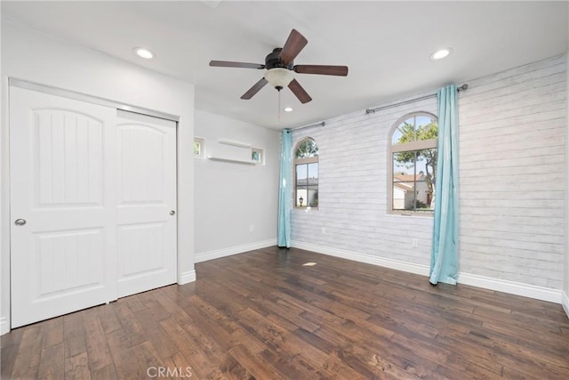 spare room featuring a ceiling fan, wood finished floors, baseboards, and brick wall