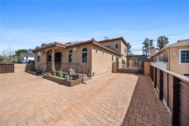 rear view of house featuring stucco siding, a patio, and fence