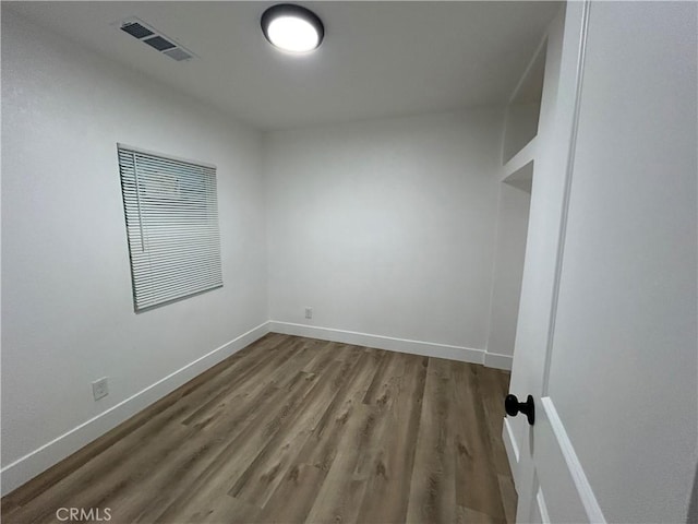 spare room with visible vents, baseboards, and wood finished floors