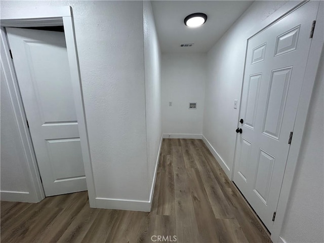 corridor featuring visible vents, baseboards, and wood finished floors