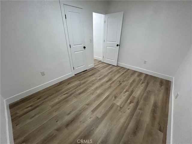 unfurnished room with baseboards and wood finished floors