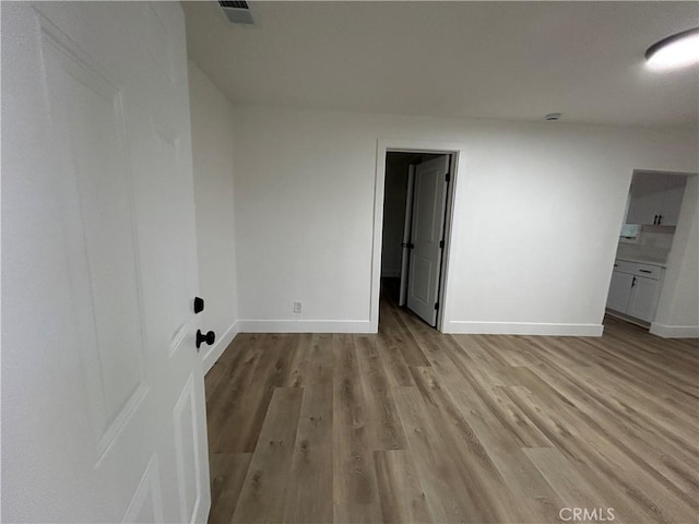 empty room featuring baseboards, visible vents, and light wood finished floors