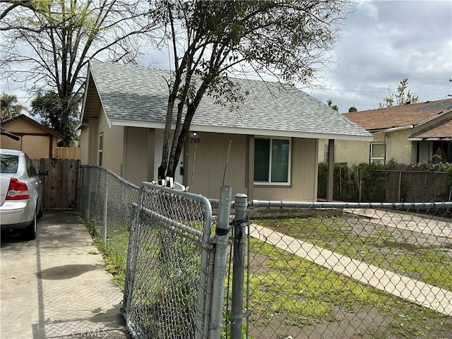 bungalow-style home with a gate, a fenced front yard, and a shingled roof