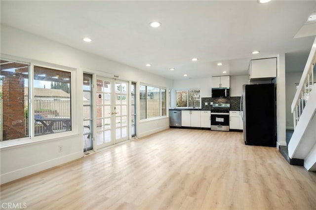 kitchen featuring tasteful backsplash, white cabinets, stainless steel appliances, and light wood-type flooring