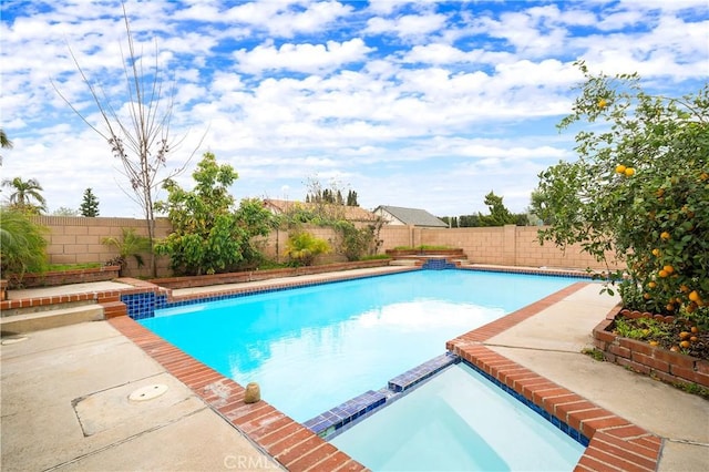 view of pool featuring a patio, a fenced backyard, and a pool with connected hot tub