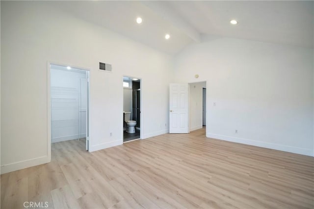 unfurnished bedroom with visible vents, a walk in closet, beam ceiling, light wood-style flooring, and high vaulted ceiling