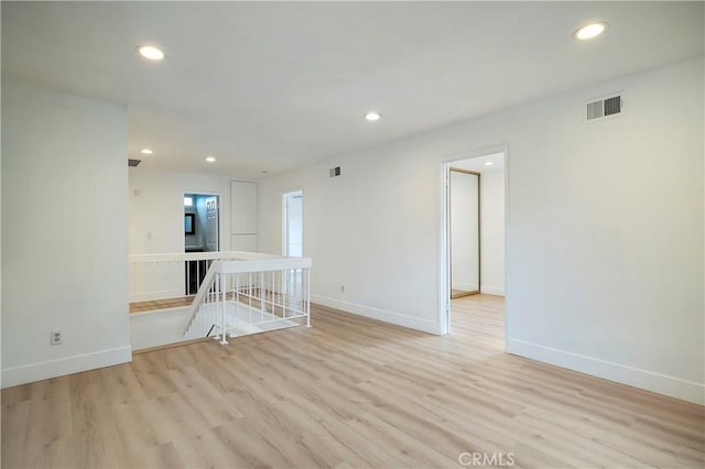 empty room with light wood-type flooring, visible vents, baseboards, and recessed lighting