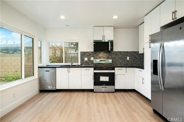 kitchen with dark countertops, backsplash, appliances with stainless steel finishes, and a sink