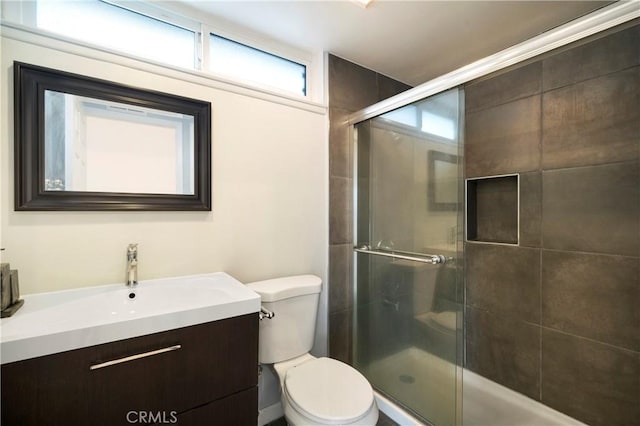 bathroom with a shower stall, toilet, and vanity