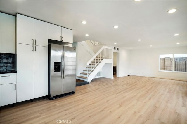 kitchen with light wood-type flooring, visible vents, white cabinets, and stainless steel refrigerator with ice dispenser