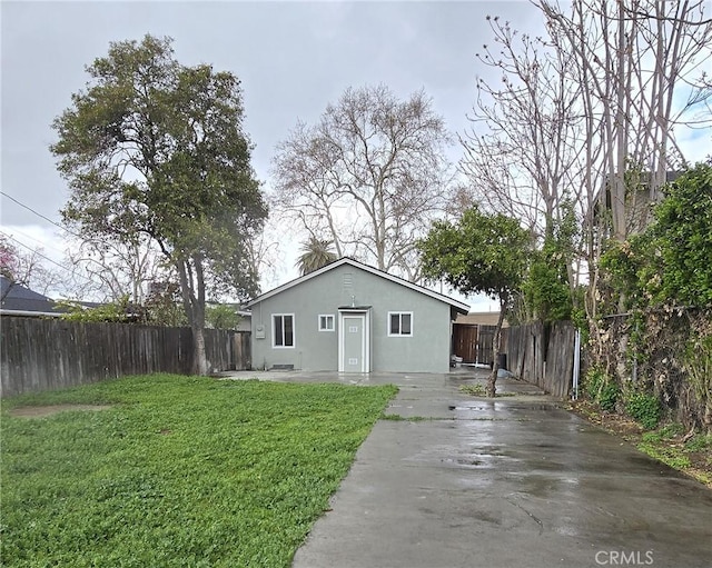 rear view of house featuring a patio, a lawn, fence, and stucco siding