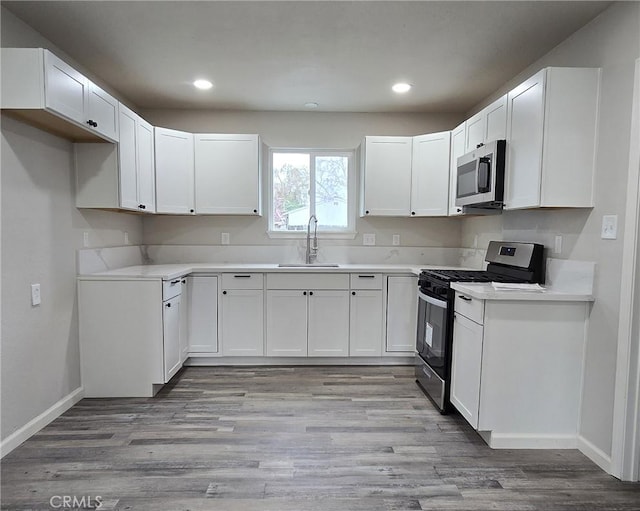 kitchen with a sink, light wood-style flooring, white cabinetry, and stainless steel appliances