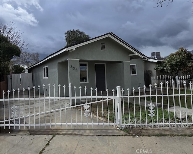 view of front of house with a fenced front yard, stucco siding, and a gate