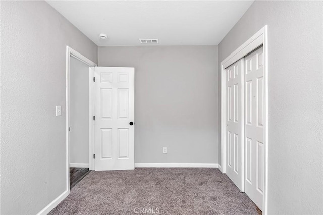 unfurnished bedroom featuring carpet flooring, a closet, baseboards, and visible vents