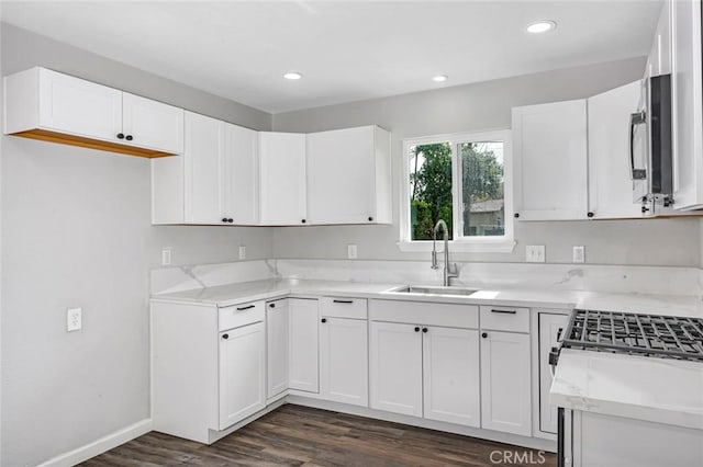 kitchen featuring white cabinets, baseboards, recessed lighting, a sink, and dark wood-style floors