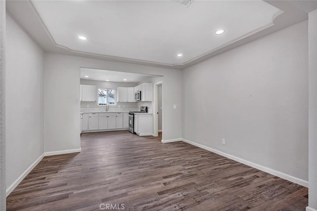 unfurnished living room featuring baseboards, dark wood-style flooring, a sink, and recessed lighting