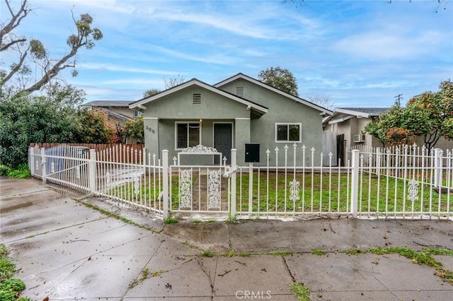 view of front facade featuring a fenced front yard, a gate, stucco siding, and a front lawn