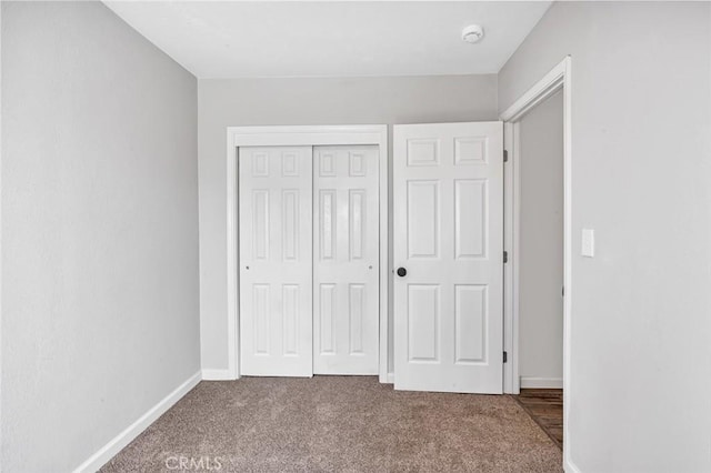 unfurnished bedroom with baseboards, carpet flooring, and a closet