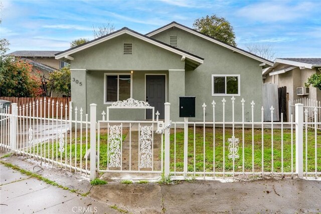view of front facade featuring stucco siding, a fenced front yard, a porch, and a front yard