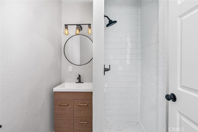 bathroom with a tile shower and vanity